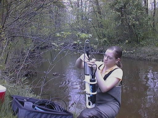 Sarah Barnhard holds a water quality sonde near a stream